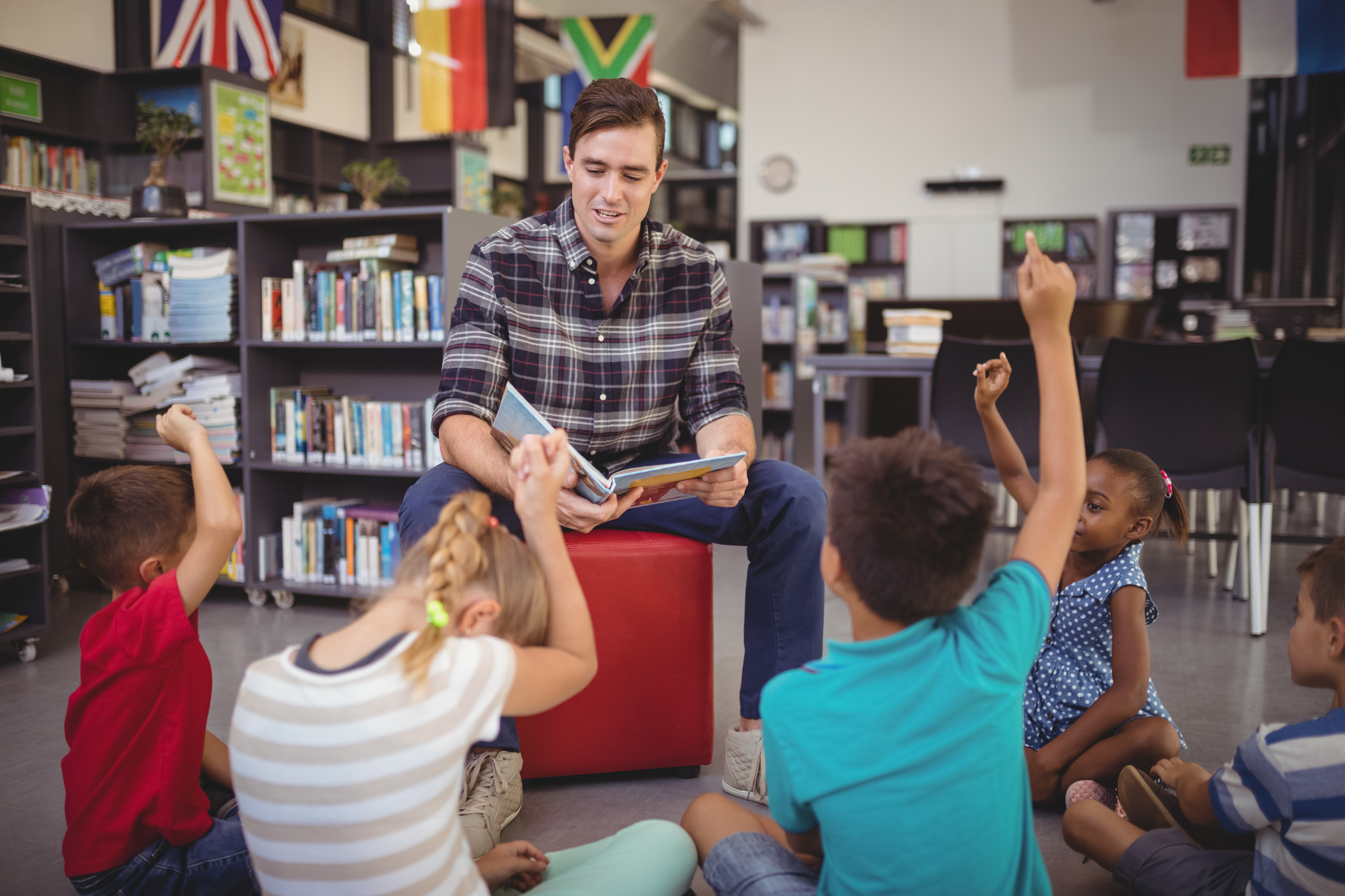 Mann liest Kindern in Bibliothek vor