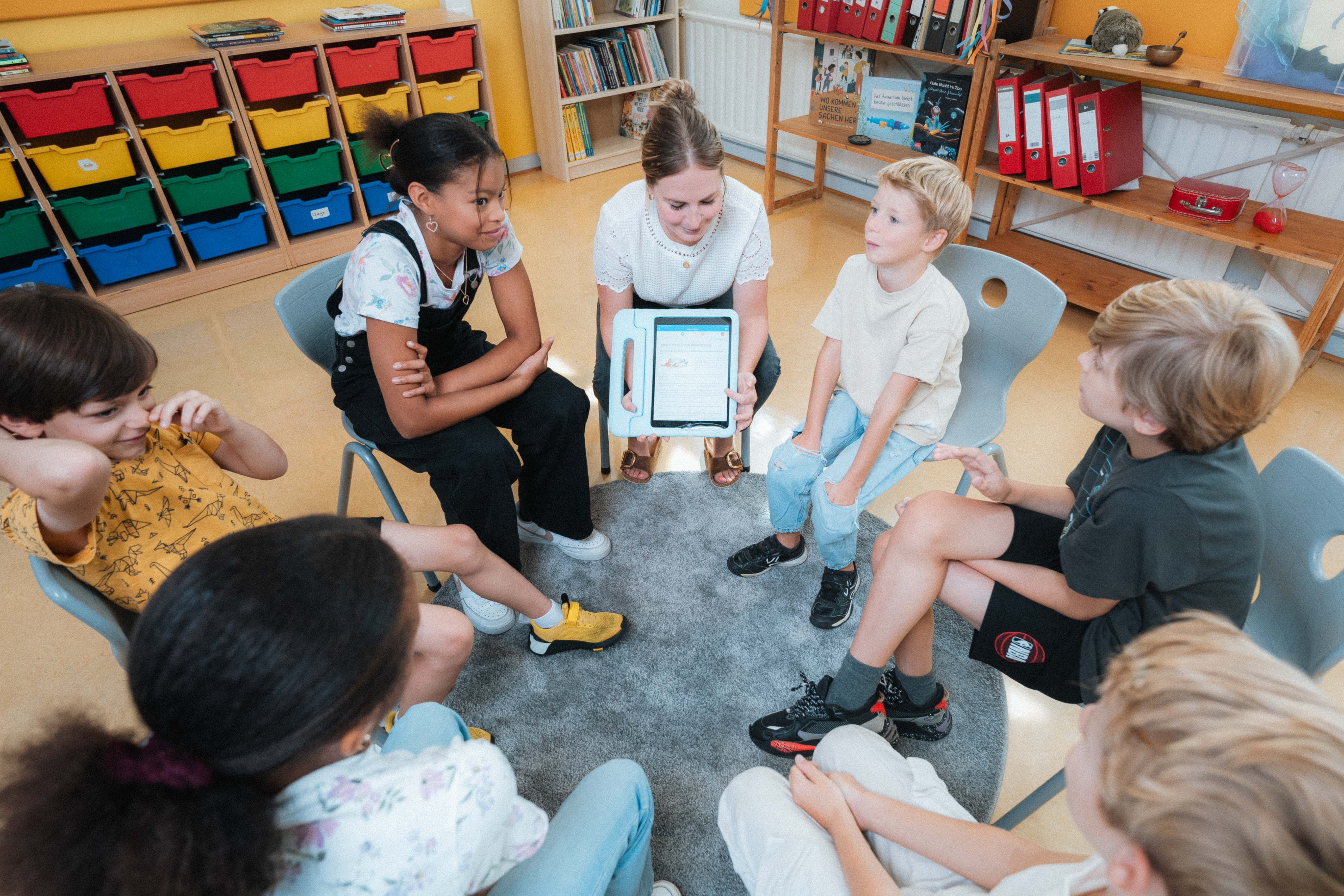 Frau zeigt Kindern etwas auf einem Tablet