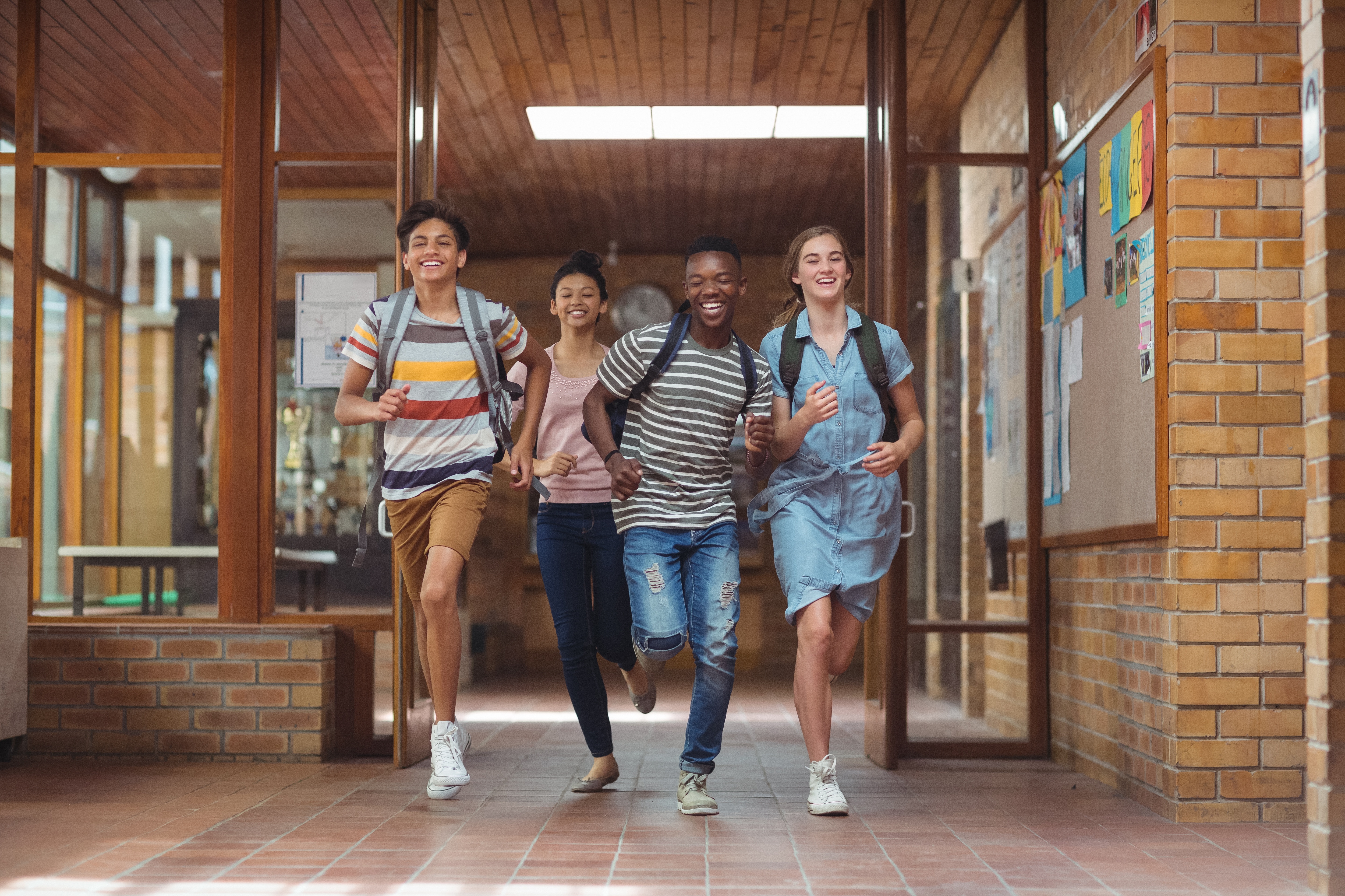 Vier Jugendliche laufen fröhlich aus Schule