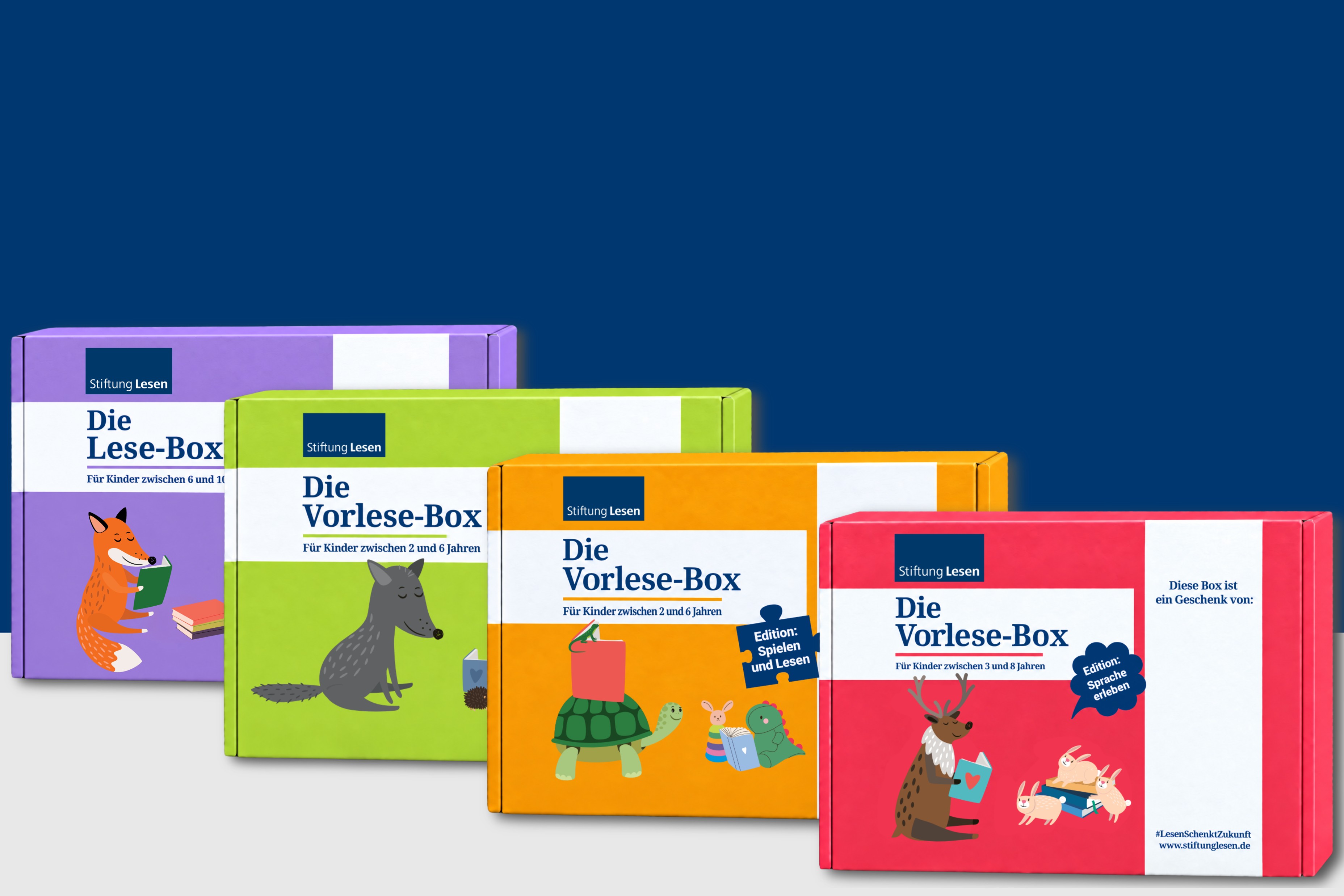 Vier bunte Bücherboxen der Stiftung Lesen vor dunkelblauem Hintergrund: eine lilafarbene Lese-Box sowie drei Vorlese-Boxen in Grün, Orange und Rot. Die Boxen sind mit lesenden Tieren illustriert und richten sich an Kinder verschiedener Altersgruppen.