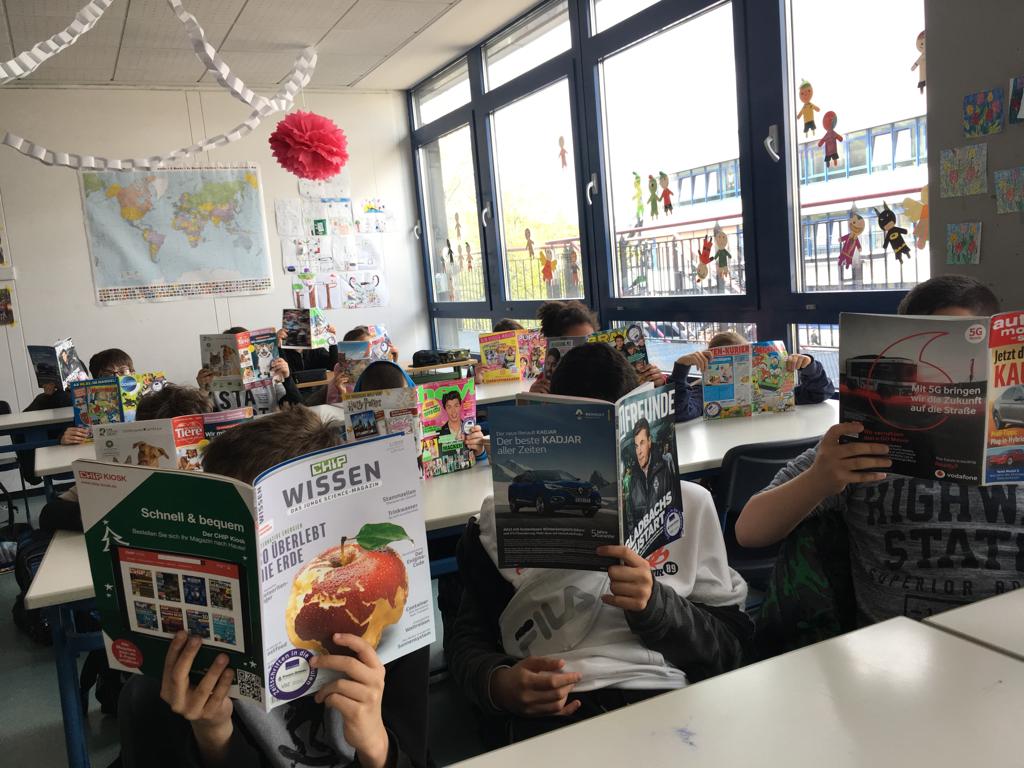 Eine Schulklasse hält Zeitschriften Cover ins Bild