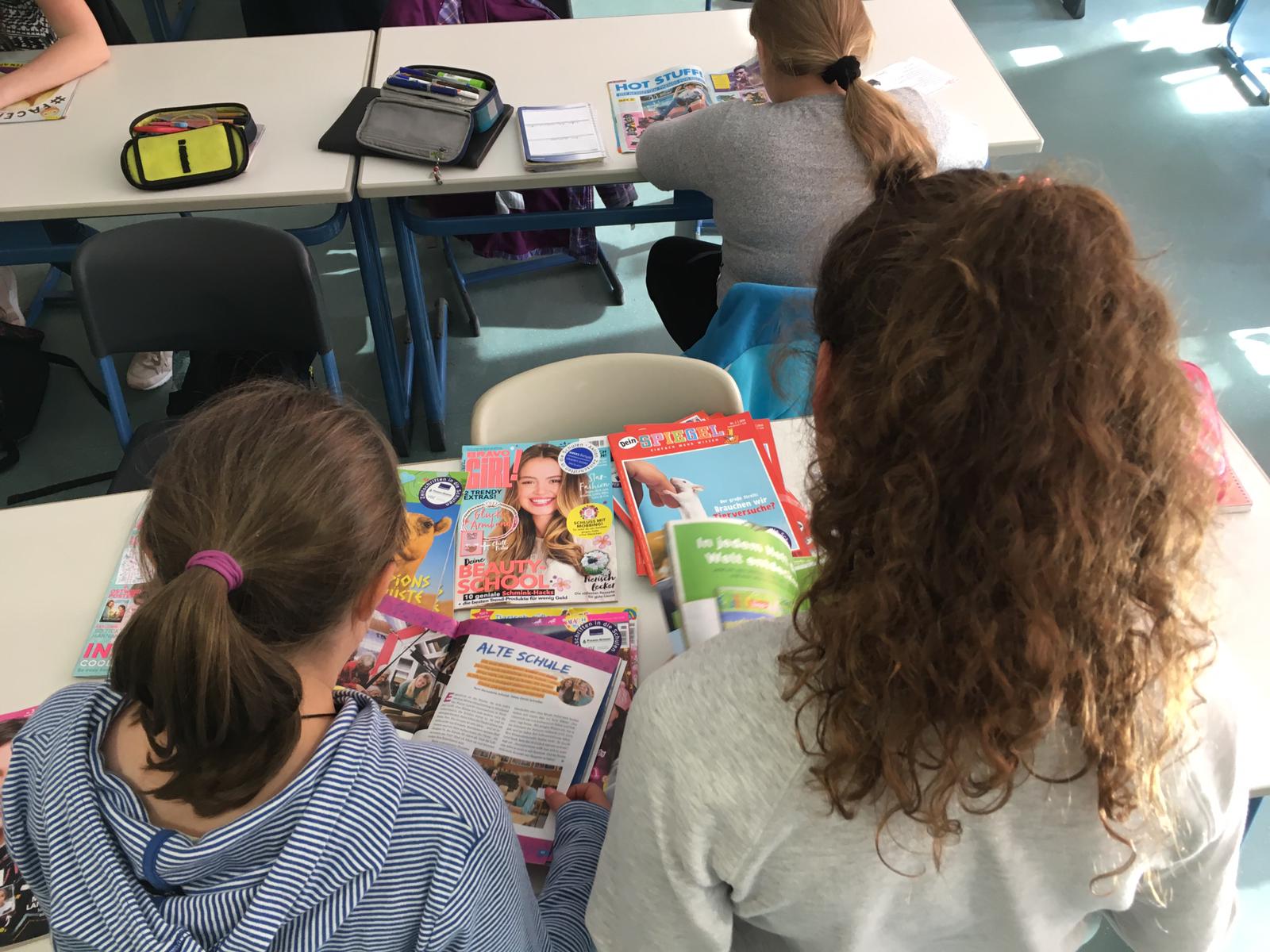 Schülerinnen schauen sich Zeitschriften an