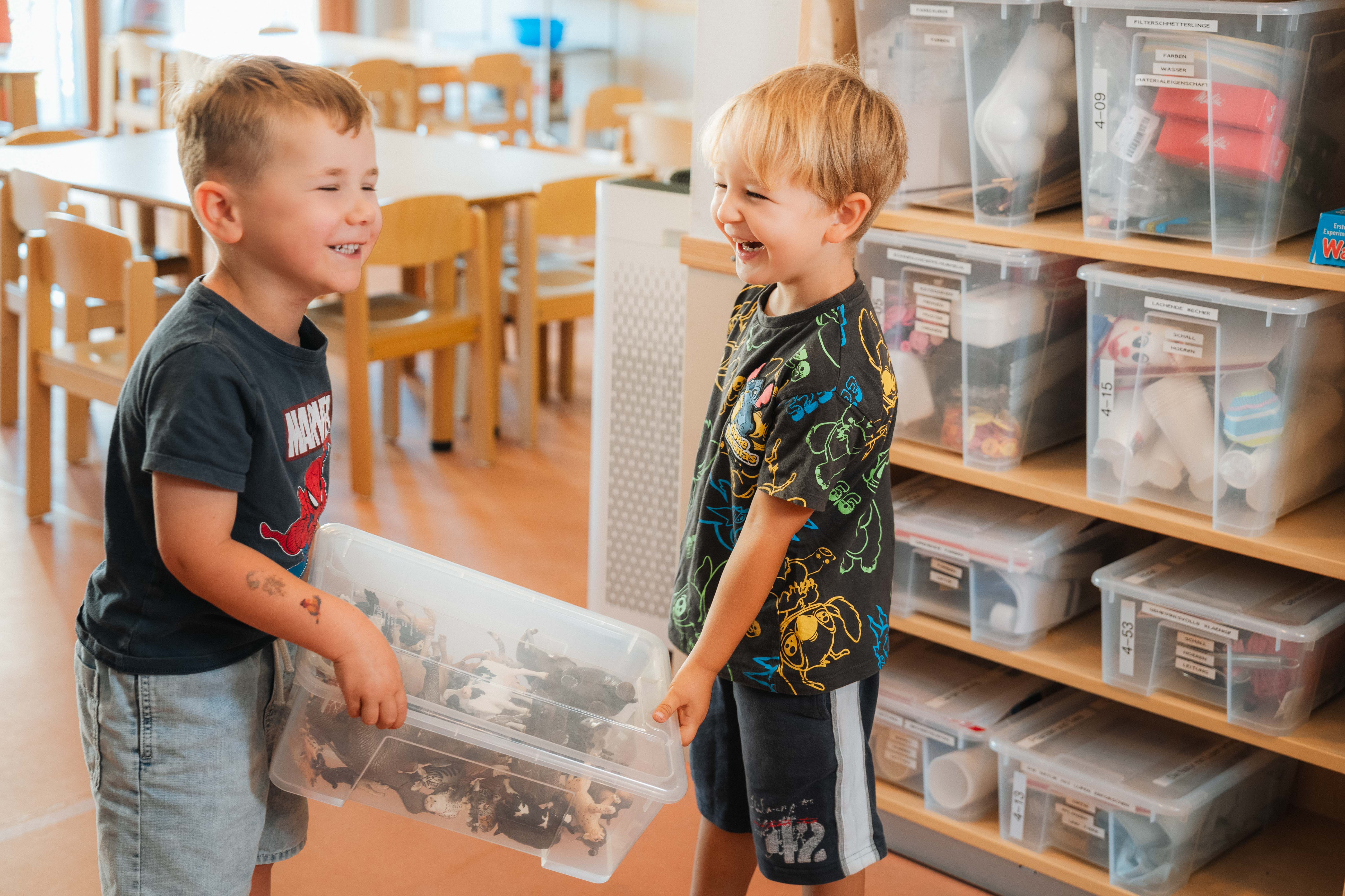 Zwei Jungen halten eine Plastik Box fest und lachen