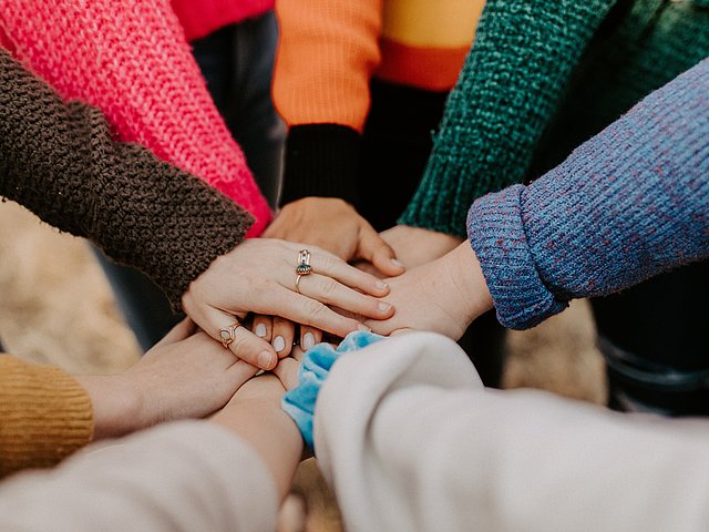 Menschen unterschiedlicher Herkunft legen die Hände übereinander