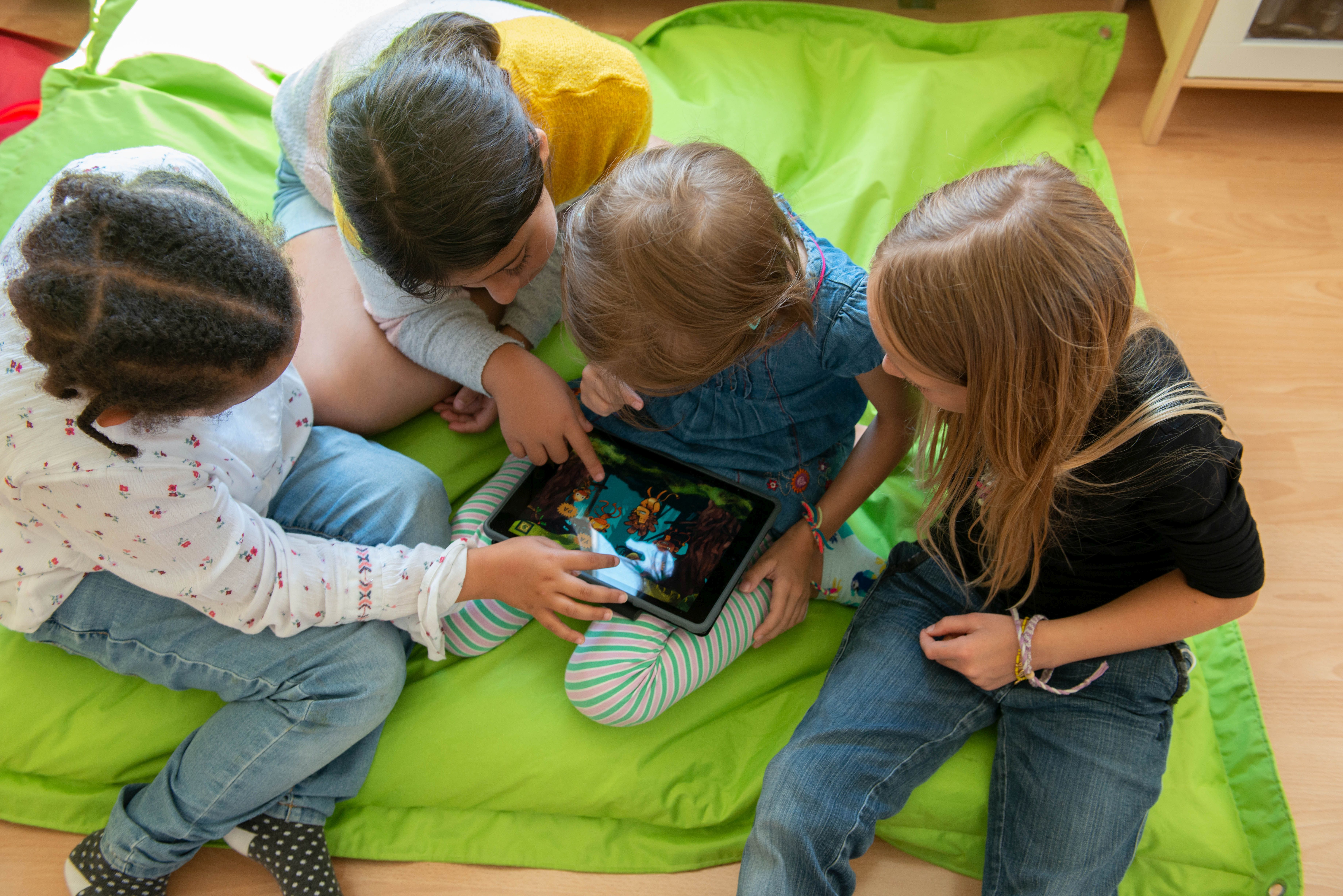 Kinder beschäftigen sich mit einem Tablet im Leseclub