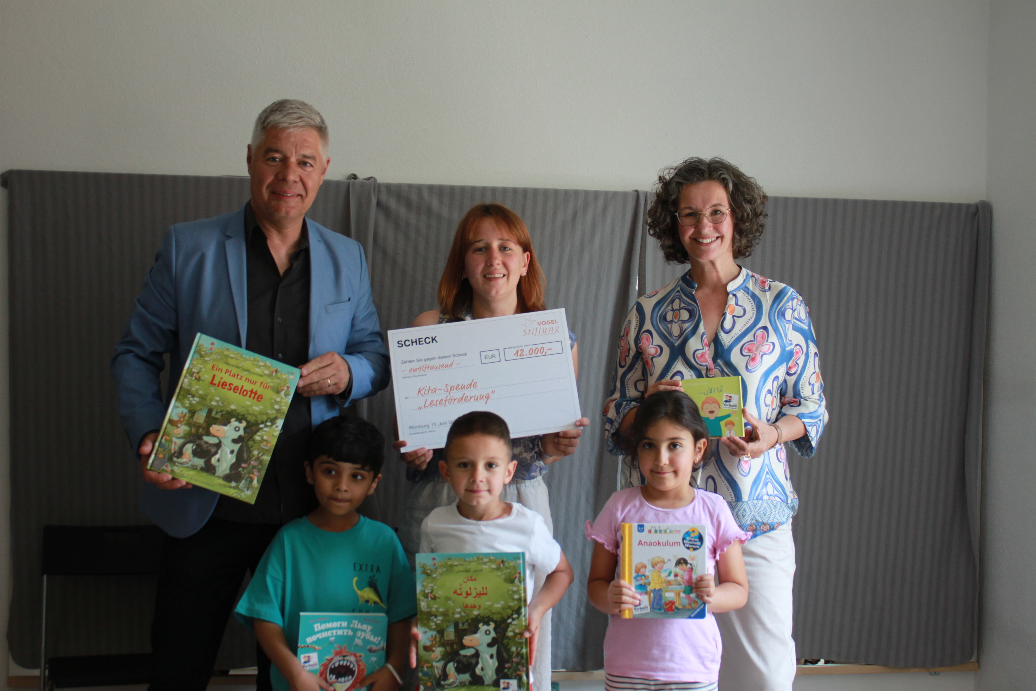 Auf dem Bild sieht man Gunther Schunk, Vorstandsvorsitzender der Vogel Stiftung Dr. Eckernkamp, Frau Ann-Sophie Lorey, die Leitung des Kinderhauses Kleiner Globus, Sabine Uehlein, Geschäftsführerin Programme Stiftung Lesen mit Kindern aus der Einrichtung und mehrsprachigen Lesemedien.