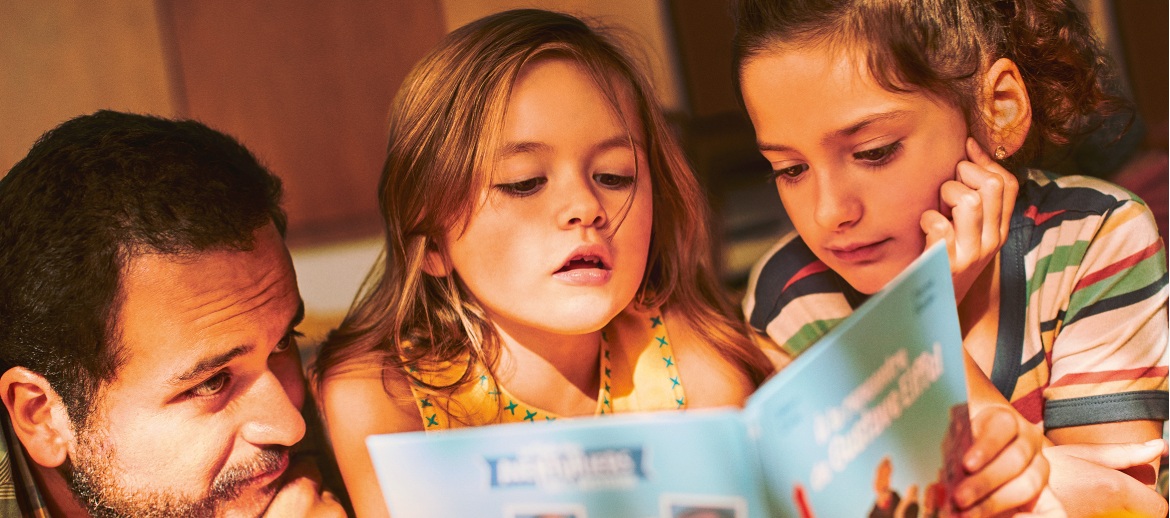 Ein Vater mit zwei Kindern liest im Buch aus dem Happy Meal