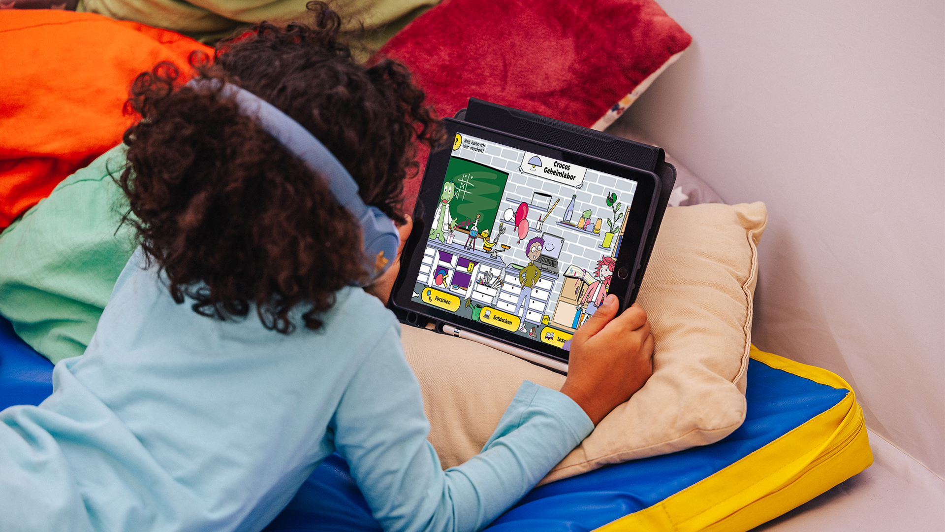 Ein Kind mit Kopfhörern verfolgt gespannt das Geschehen auf einem Tablet