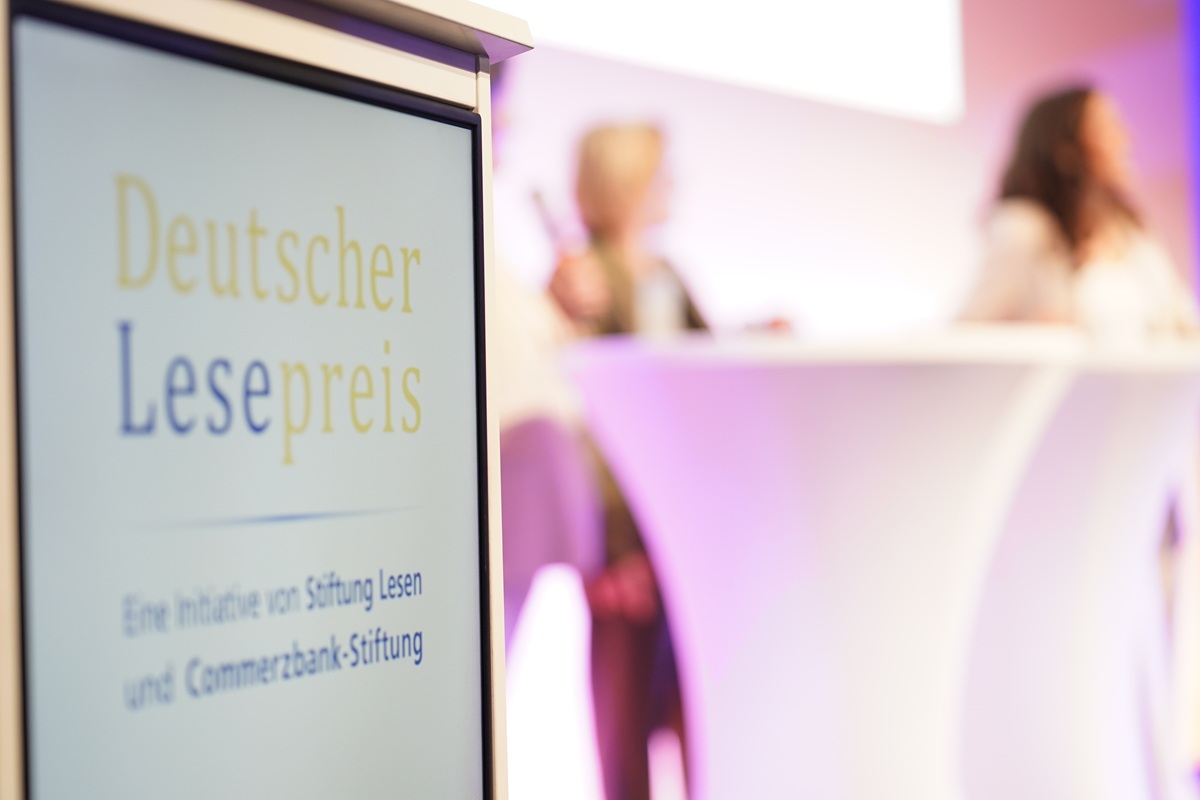 "Deutscher Lesepreis"‑Schild im Vordergrund, die Bühne ist unscharf im Hintergrund