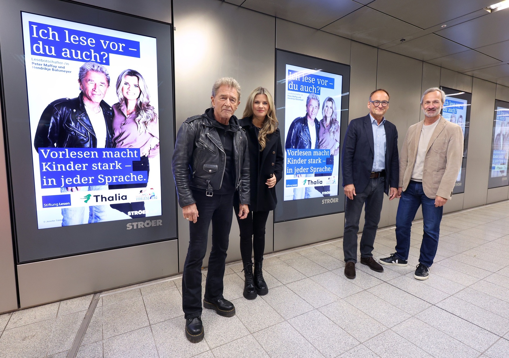 Peter Maffay und Hendrikje Balsmeyer rufen gemeinsam mit Thomas Rathnow, Vorstandsvorsitzender der Stiftung Lesen, und Stefan Helbig, Geschäftsführer der Ströer Deutsche Städte Medien GmbH stehen vor digitalen Plakaten der Vorlesekampagne „Ich lese vor – du auch?“ in einer U-Bahn-Station und rufen zum Vorlesen auf