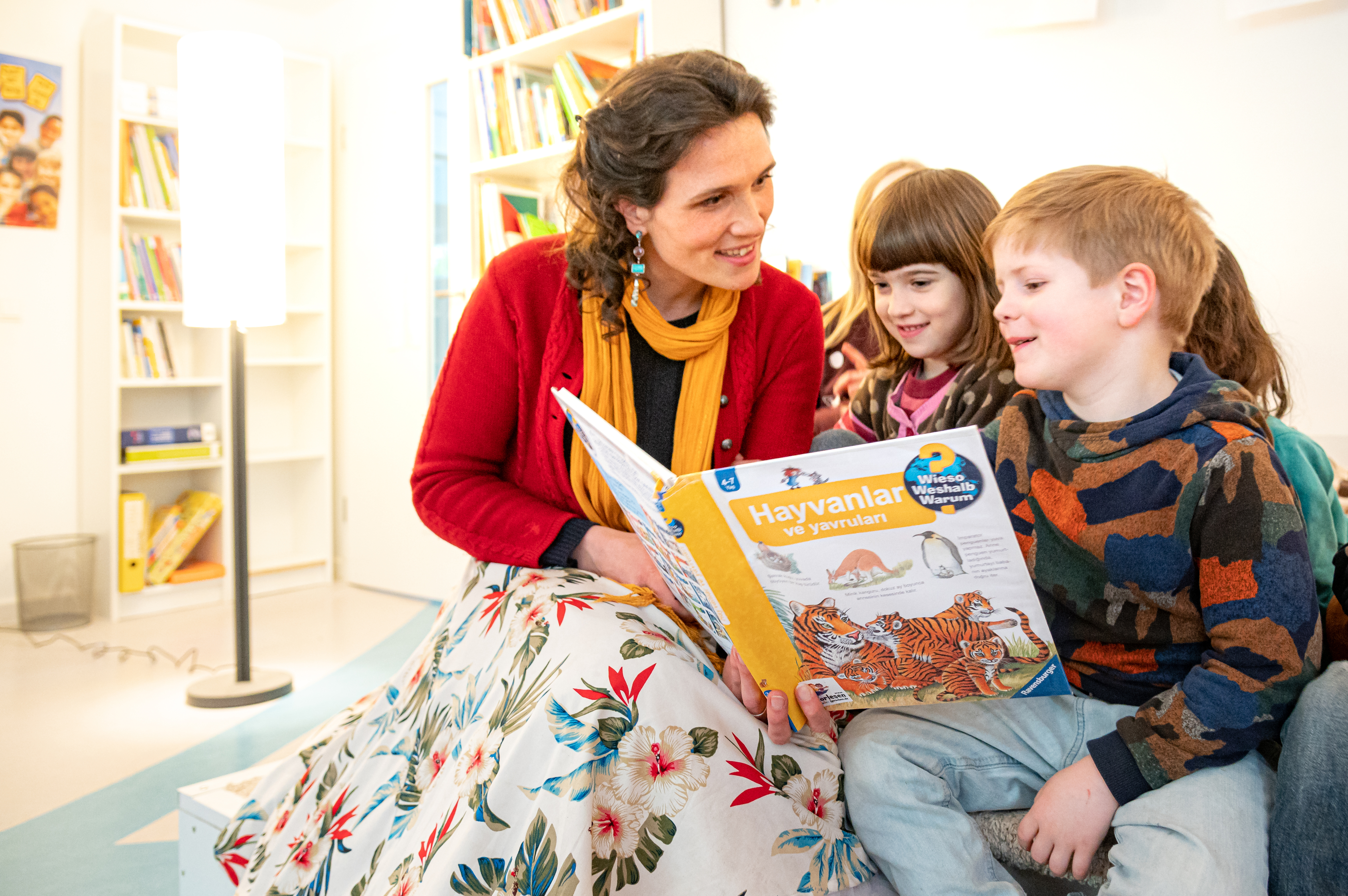 Frau liest in einer Kita Kindern aus einem "Vorlesen in allen Sprachen"-Titel vor