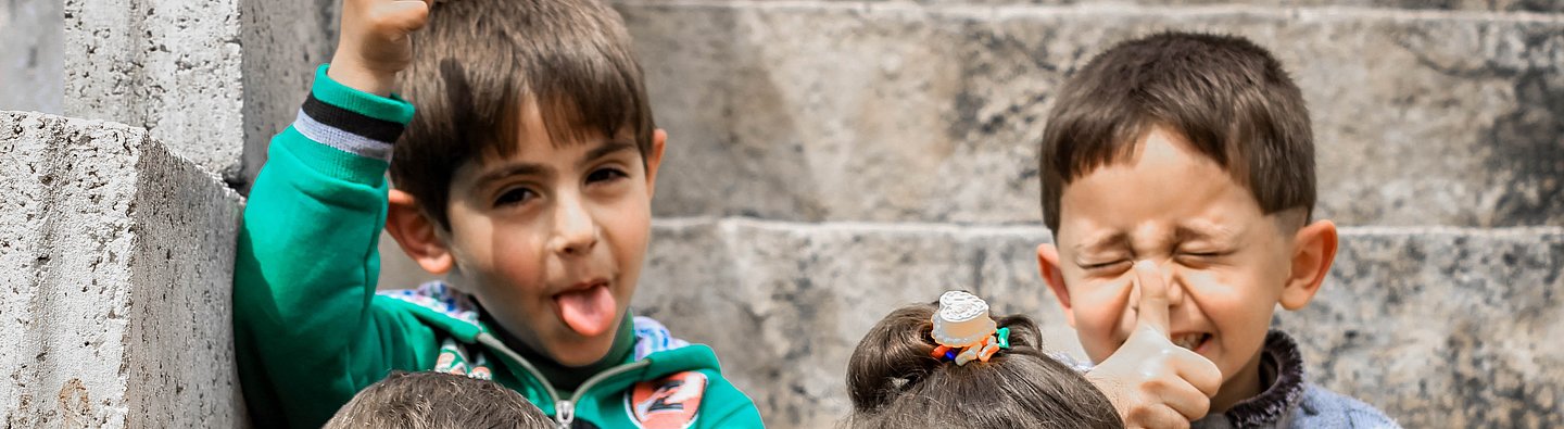 Vier Kinder sitzen auf einer Treppe und ziehen Grimassen