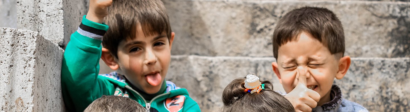 Vier Kinder sitzen auf einer Treppe und ziehen Grimassen