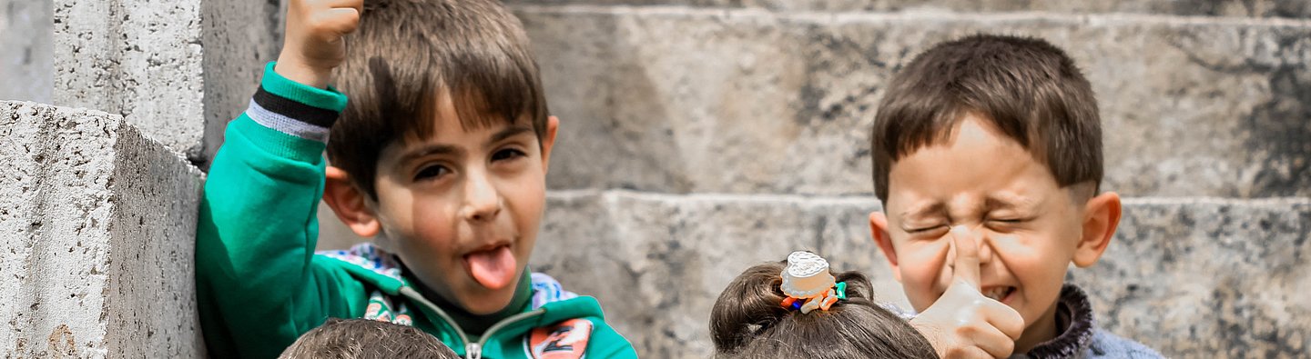 Vier Kinder sitzen auf einer Treppe und ziehen Grimassen