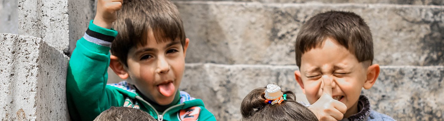 Vier Kinder sitzen auf einer Treppe und ziehen Grimassen