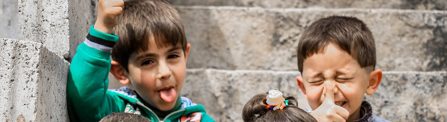 Vier Kinder sitzen auf einer Treppe und ziehen Grimassen