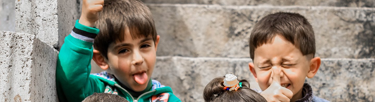 Vier Kinder sitzen auf einer Treppe und ziehen Grimassen