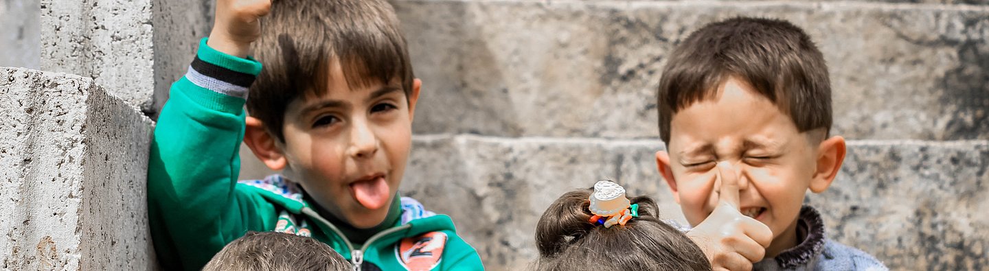 Vier Kinder sitzen auf einer Treppe und ziehen Grimassen