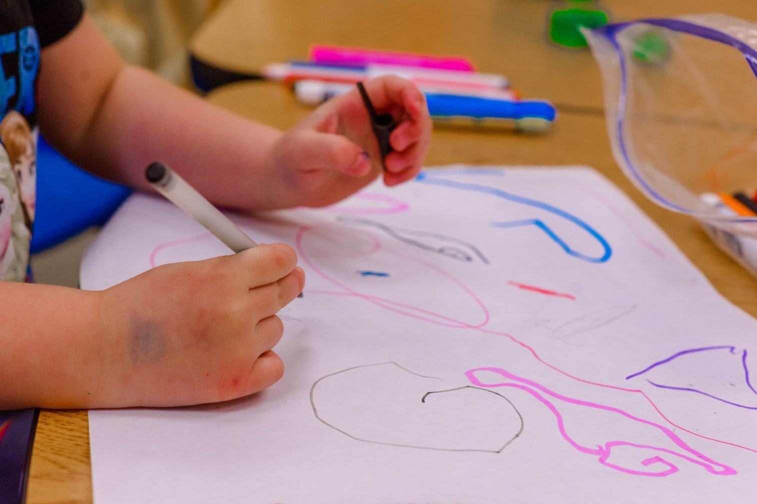 Die Hände eines kleinen Kindes malen ein buntes Bild