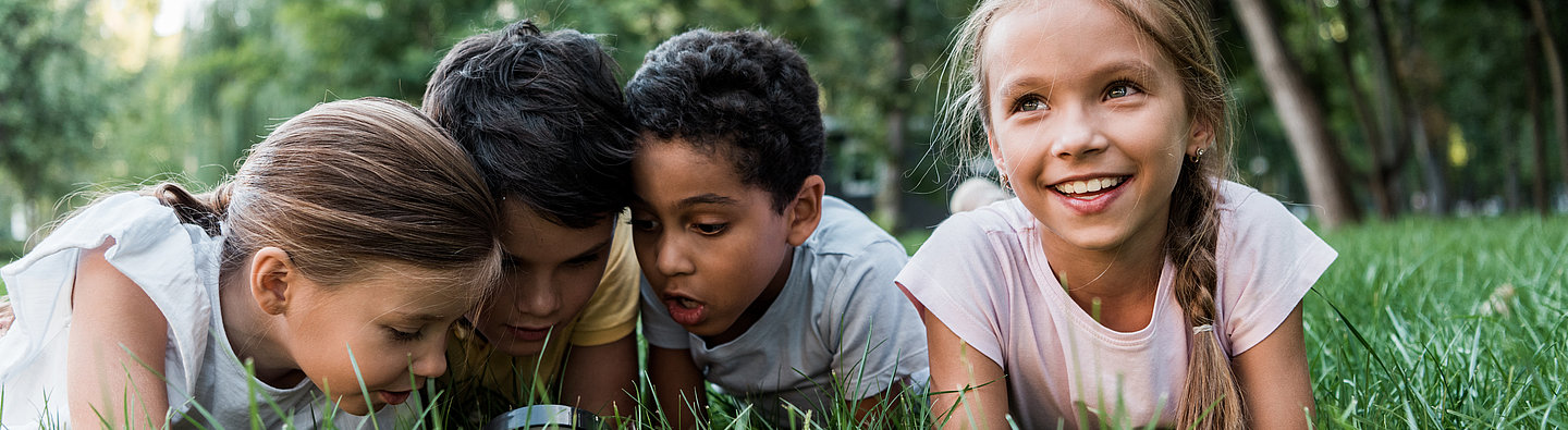 Kinder liegen auf einer Wiese und spielen