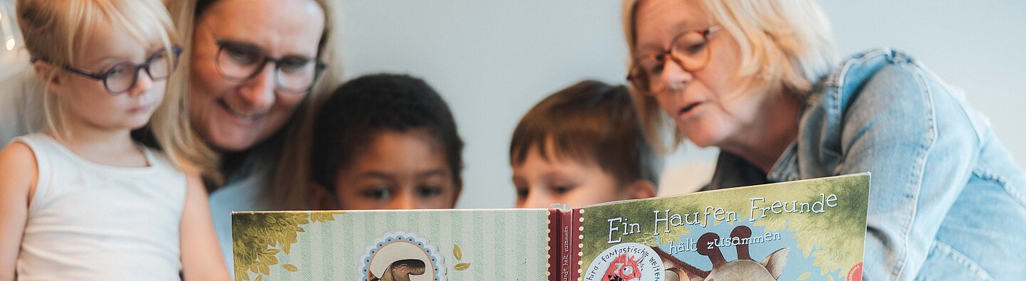 Drei Kindern wird vorgelesen