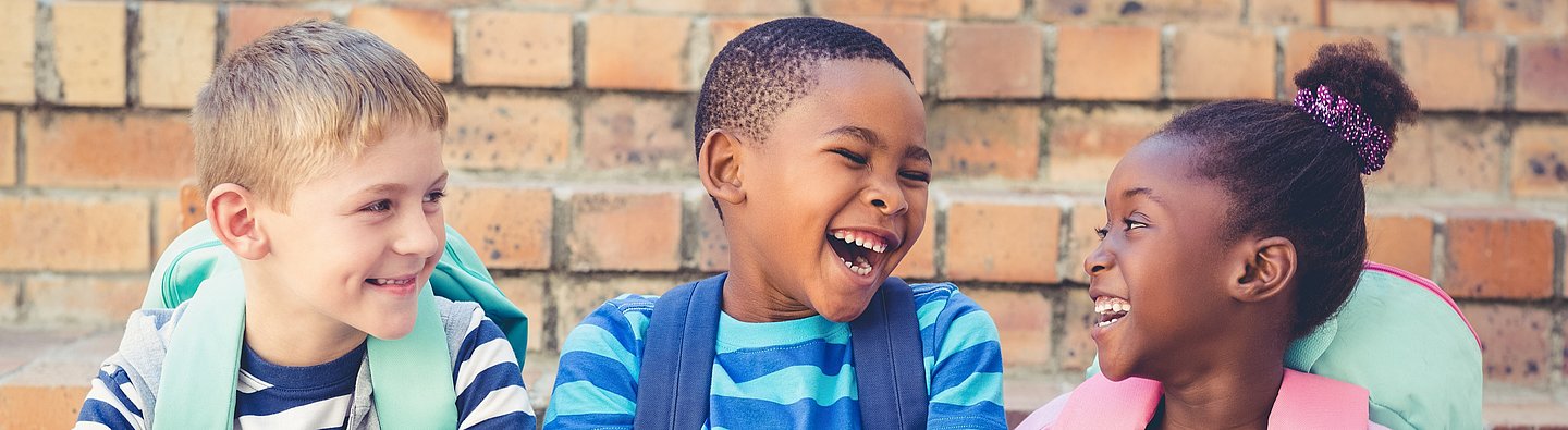 Drei Kinder lachen gemeinsam