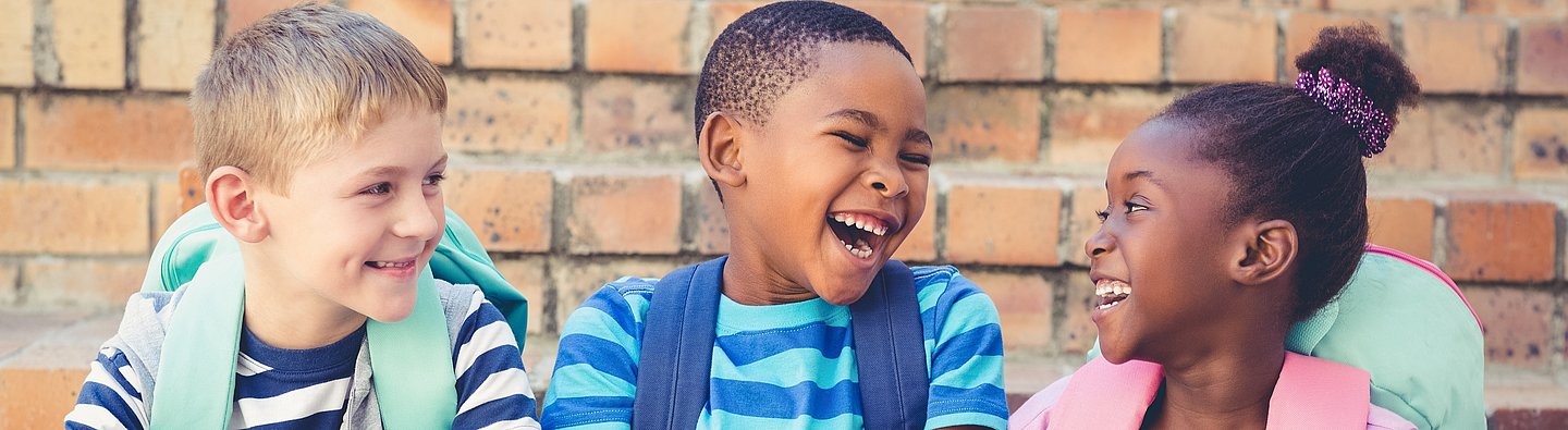 Drei Kinder lachen gemeinsam