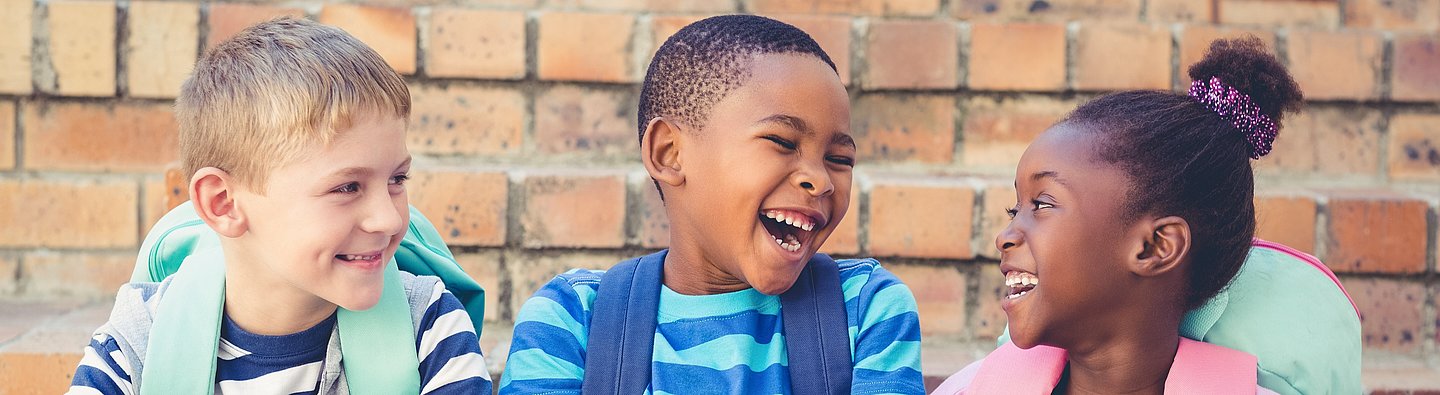 Drei Kinder lachen gemeinsam