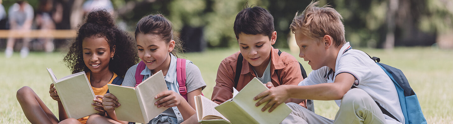 Kinder lesen auf einer Wiese
