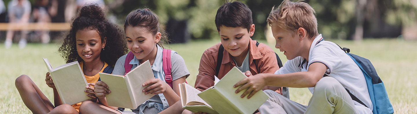 Kinder lesen auf einer Wiese