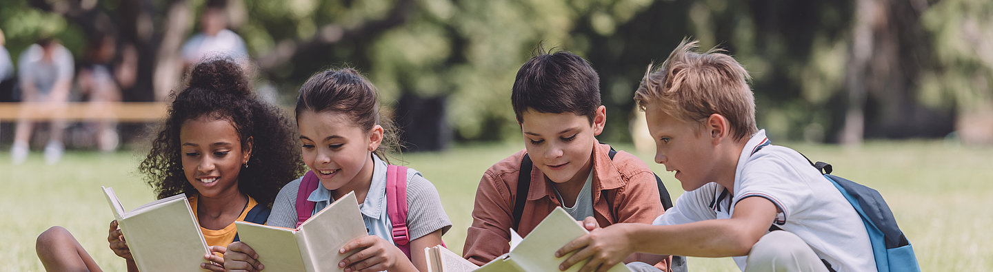 Kinder lesen auf einer Wiese