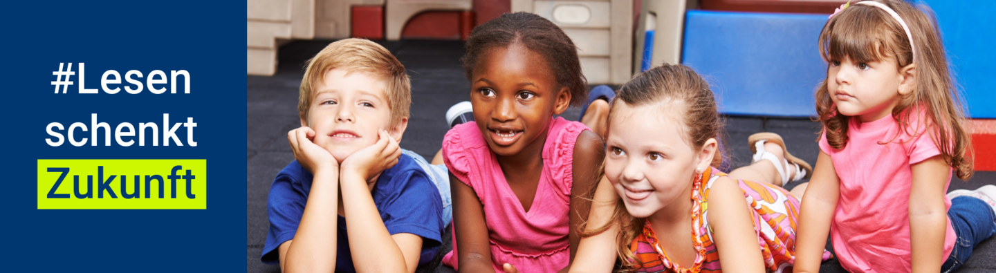 Vier Kinder im Alter von 4-5 Jahren liegen auf dem Boden und hören einer Geschichte zu. Links neben den Kinder ist der Hashtag Lesen schenkt Zukunft zu sehen