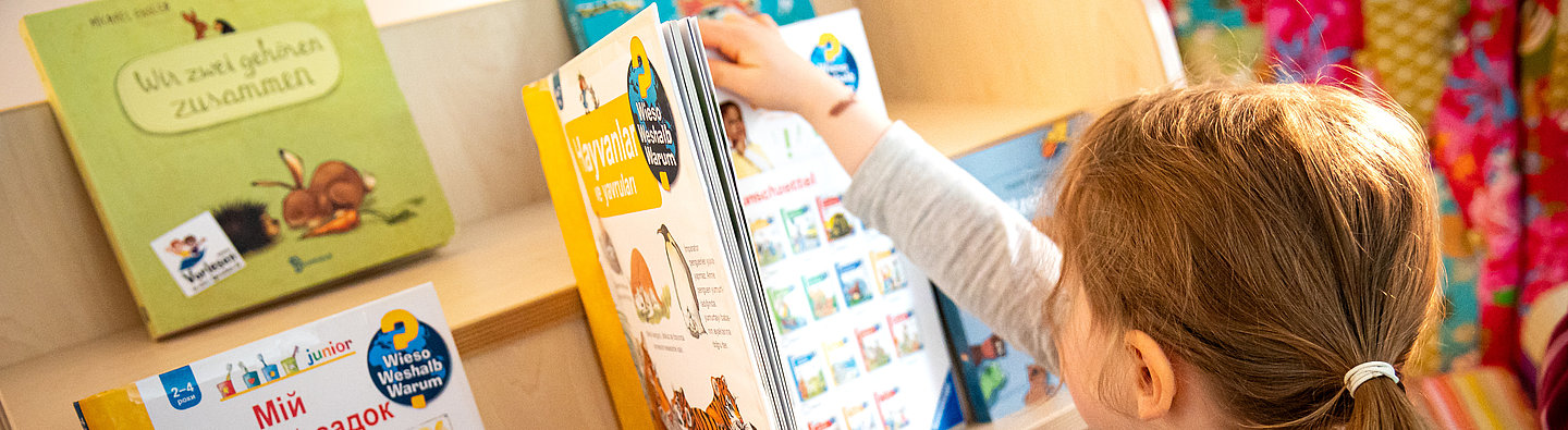 Kind sucht sich ein Buch aus der "Vorlesen in allen Sprachen"-Edition aus
