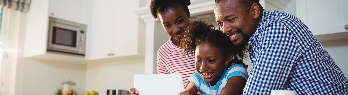 Eltern zeigen Kind etwas auf Tablet