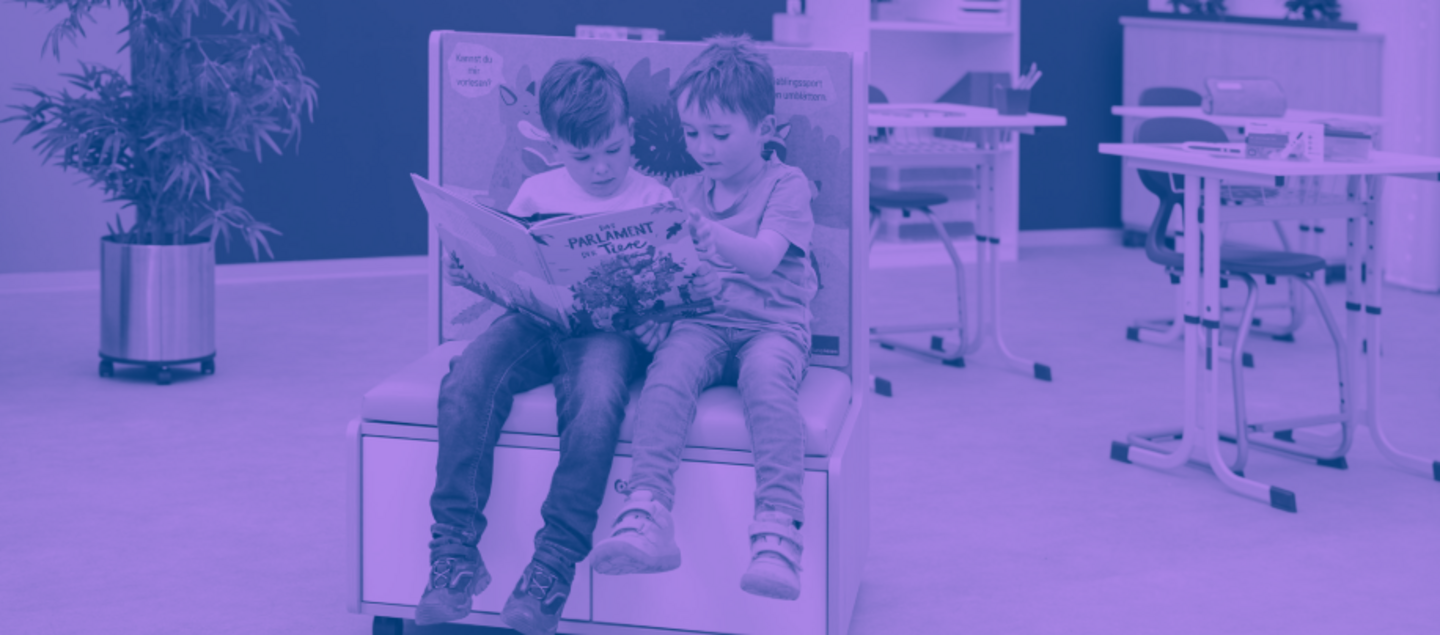 Zwei Kinder sitzen auf einem Lese-Möbel und schauen gemeinsam in ein Buch; das Bild ist violett eingefärbt.