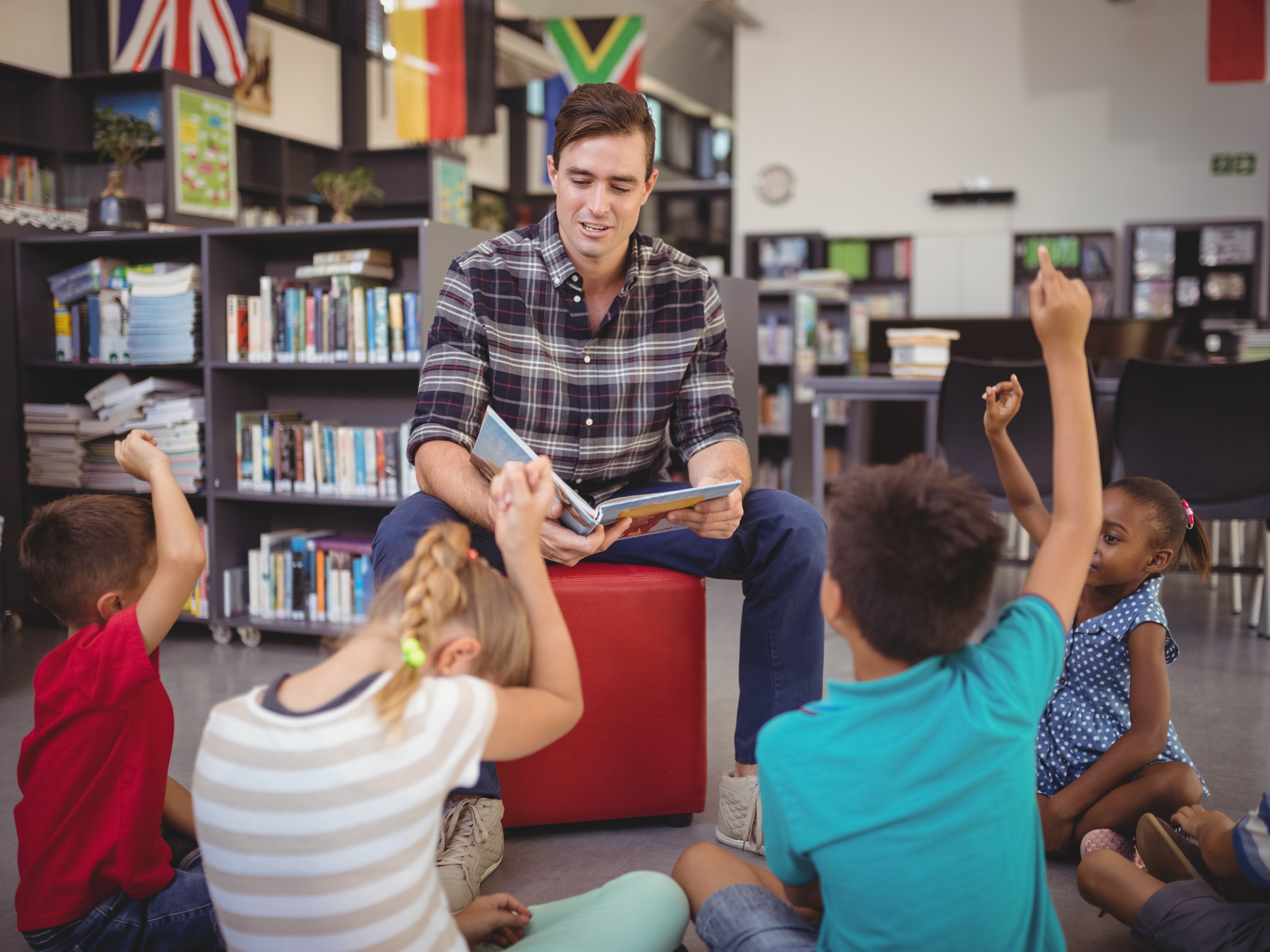 Mann liest Kindern in Bibliothek vor