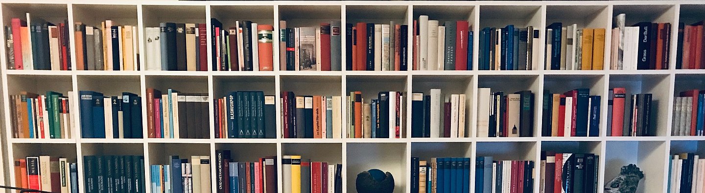 Buntes Bücherregal mit Liegestuhl im Vordergrund