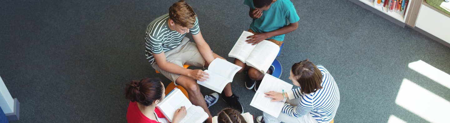 Kinder lesen im Stuhlkreis in Bibliothek