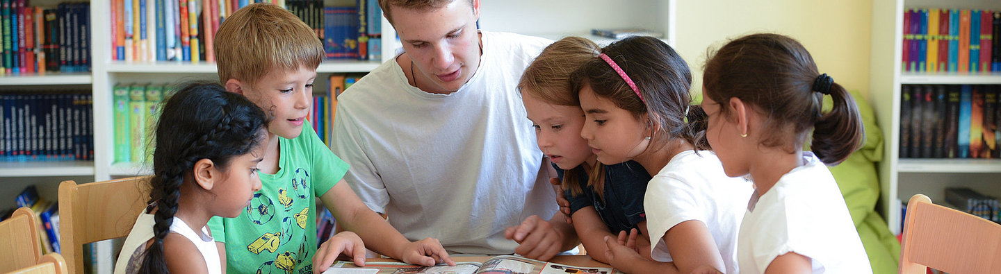 Kinder und Jugendlicher blättern gemeinsam Buch in Leseclub