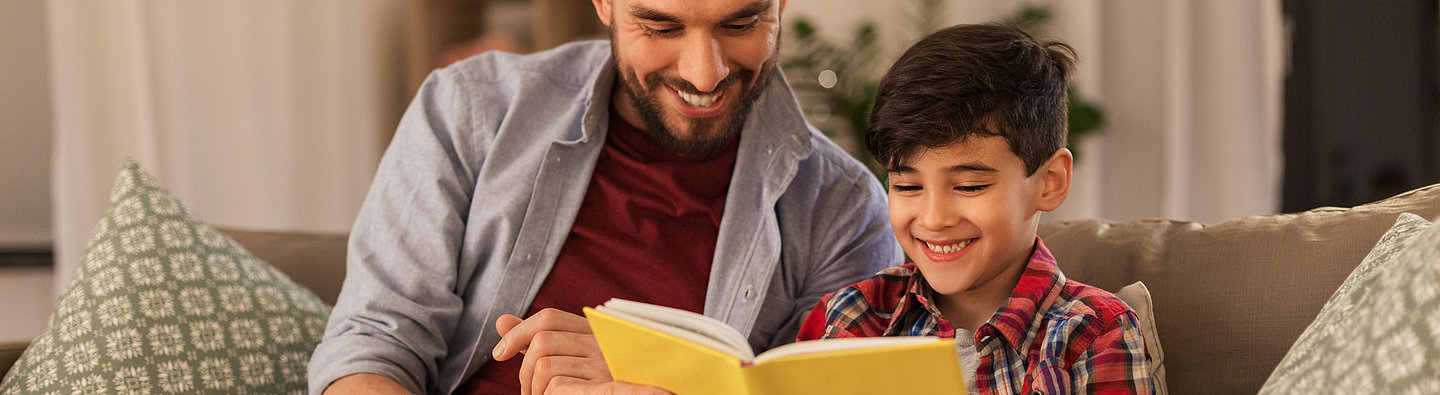 Vater und Sohn lesen auf der Couch