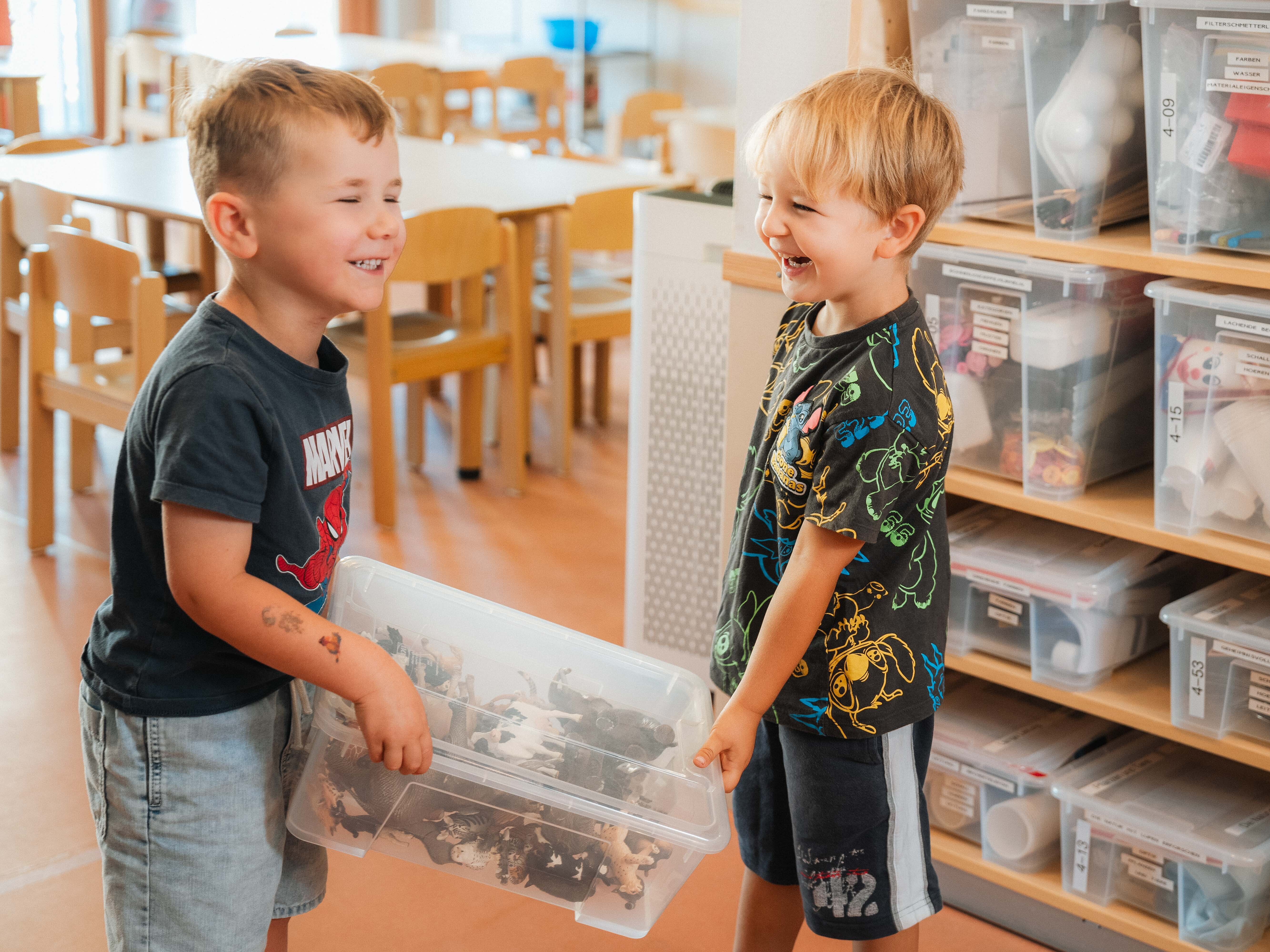 Zwei Jungen halten eine Plastik Box fest und lachen