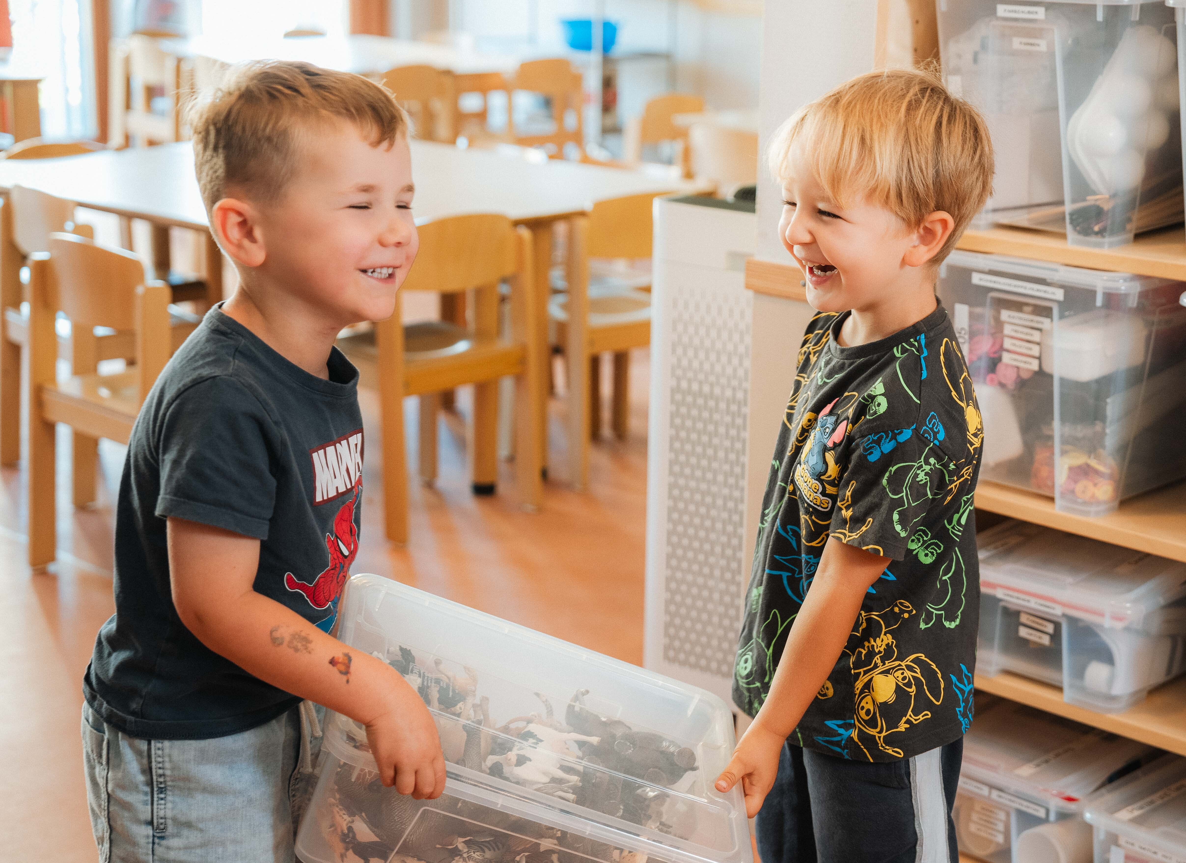 Zwei Jungen halten eine Plastik Box fest und lachen