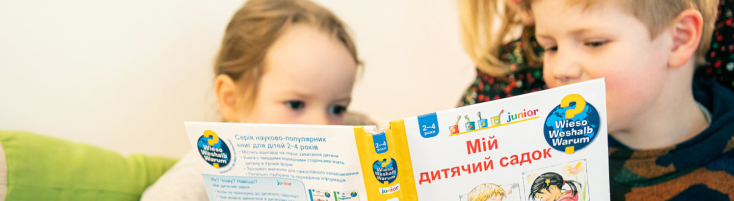 Frau liest zwei Kindern aus einem "Vorlesen in allen Sprachen"-Titel vor