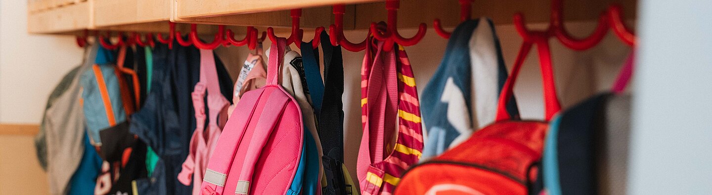 Rucksäcke hängen nebeneinander an der Garderobe