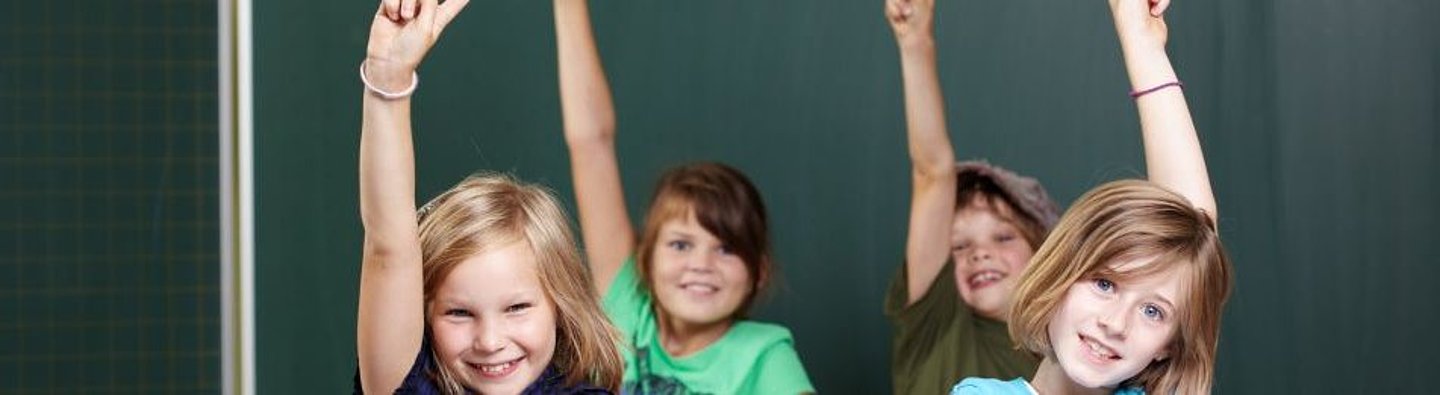 vier Kinder vor einer Tafel melden sich