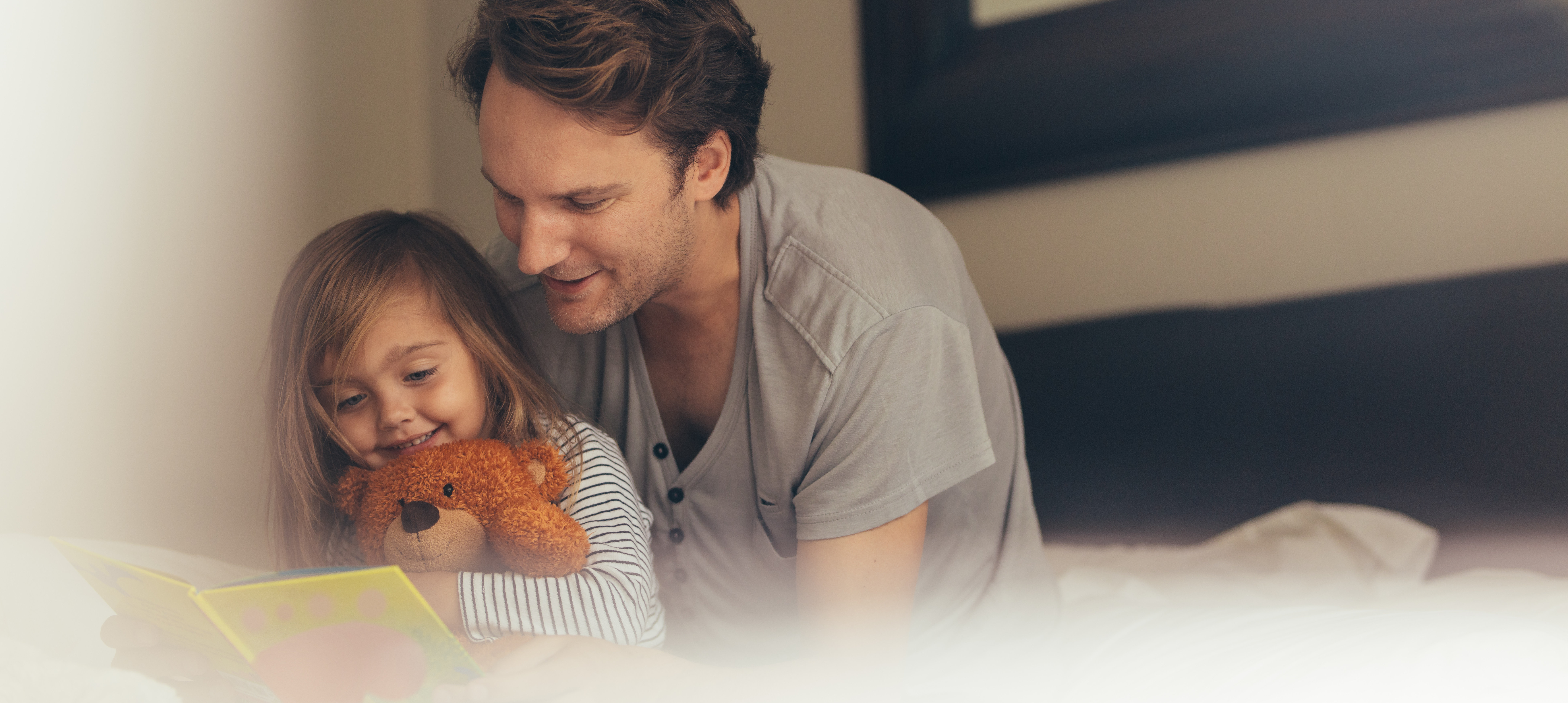 Vater und Tochter lesen gemeinsam mit Teddybär