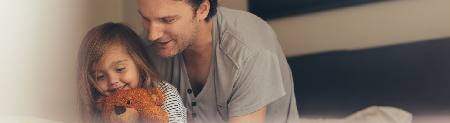 Vater und Tochter lesen gemeinsam mit Teddybär