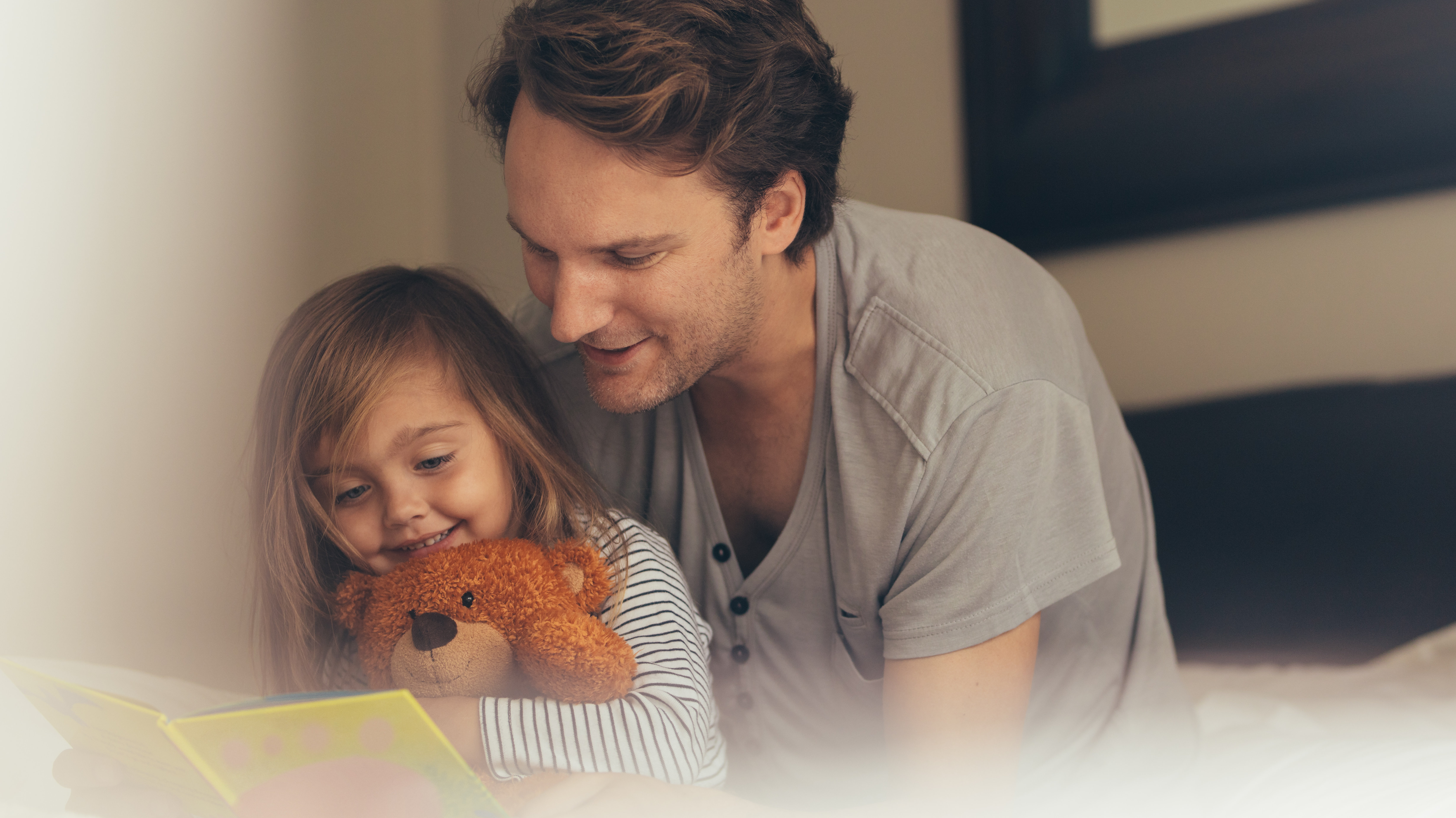 Vater und Tochter lesen gemeinsam mit Teddybär