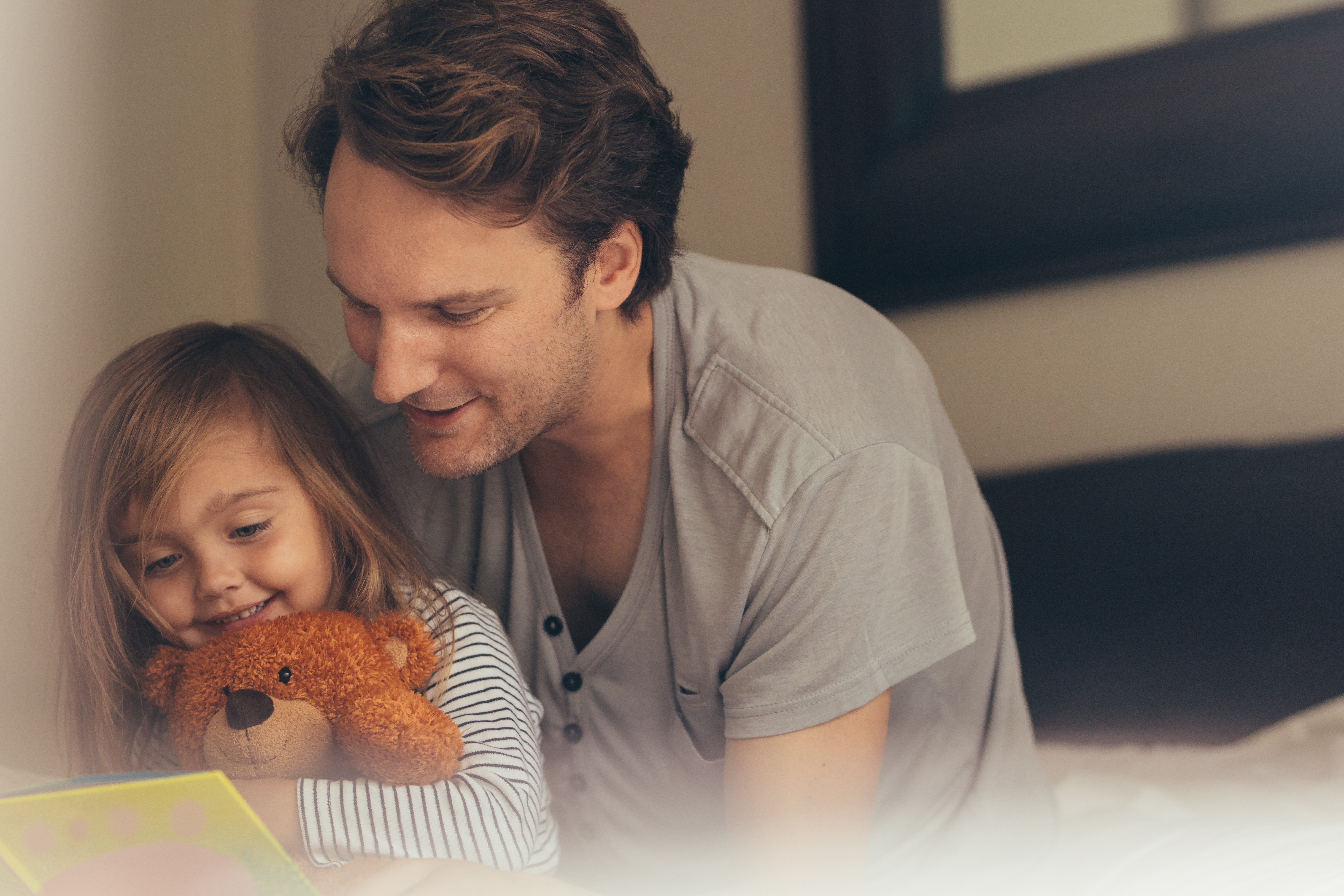 Vater und Tochter lesen gemeinsam mit Teddybär